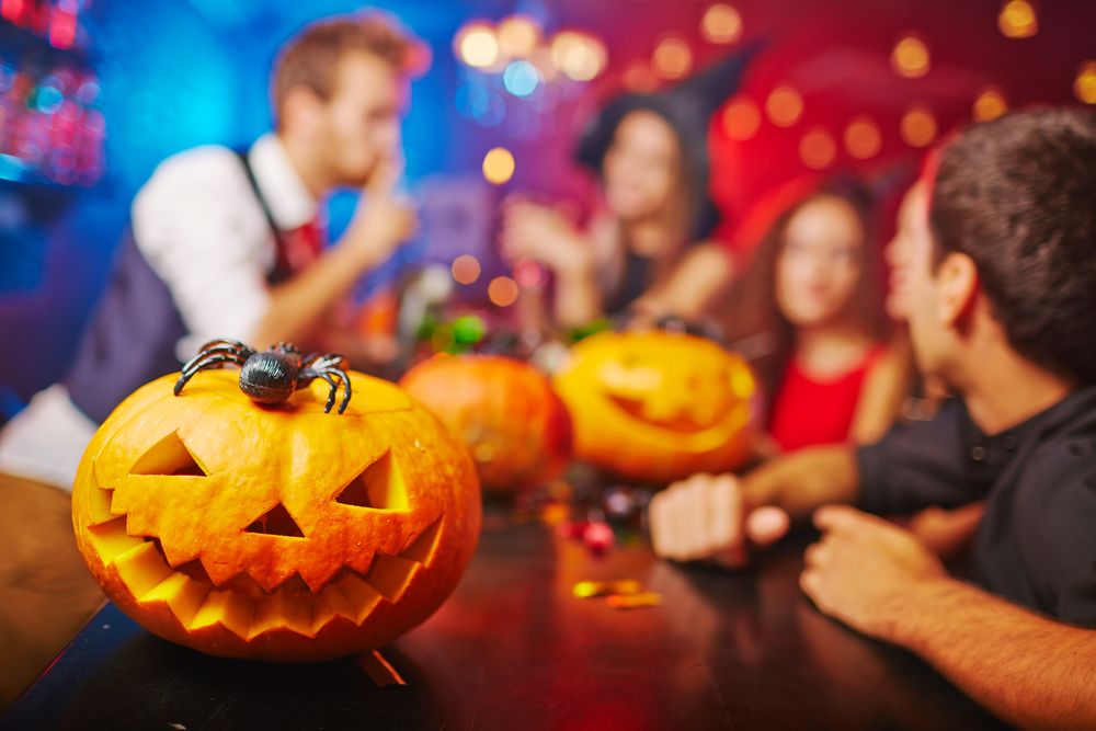 Photo of jack-o-lanterns on a bar with people partying in the background