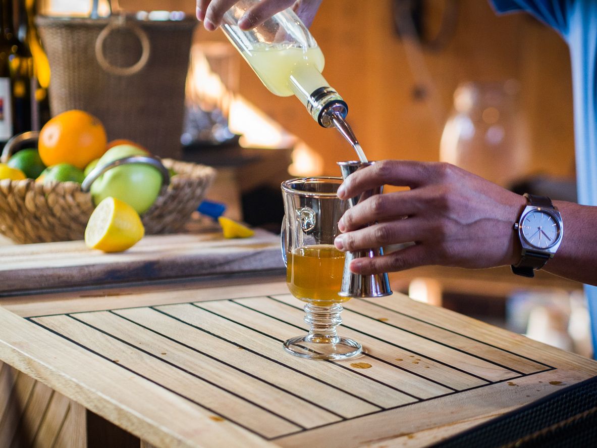 Bartender preparing a bourbon hot toddy and pouring liquor