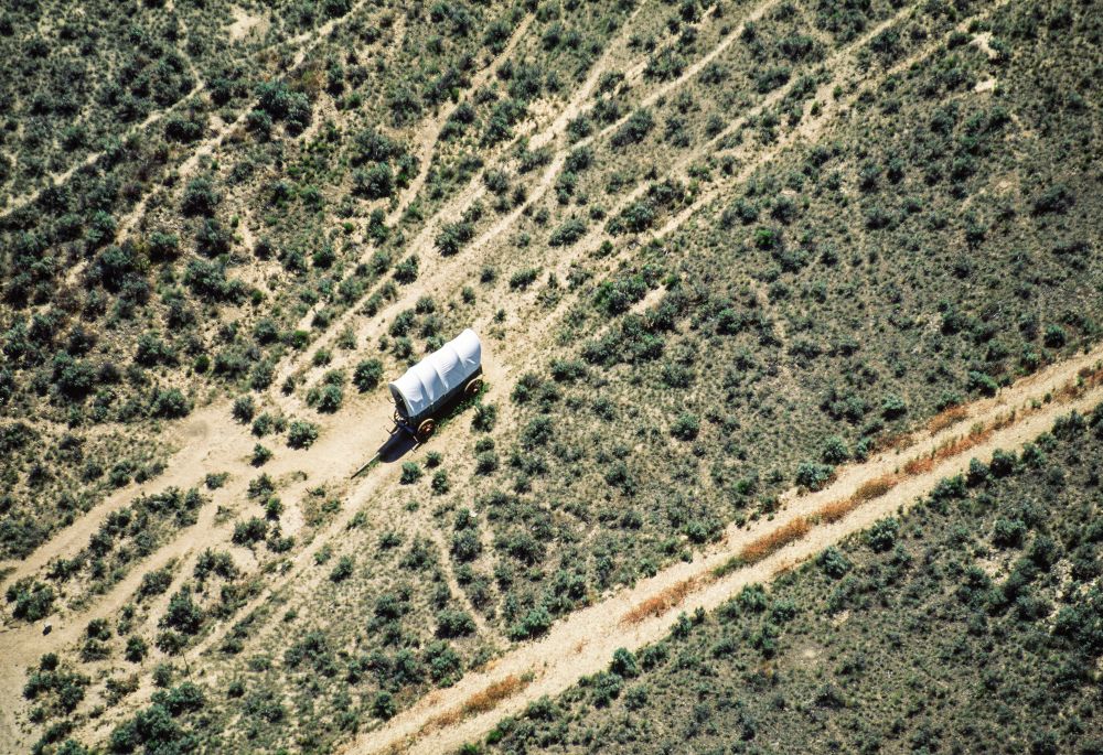 Aerial view of covered wagon on a dusty Oregon Trail road