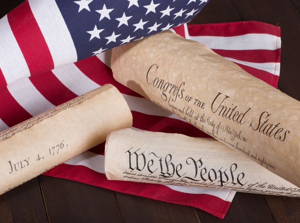 American historical documents including Bill of Rights set against patriotic American flag