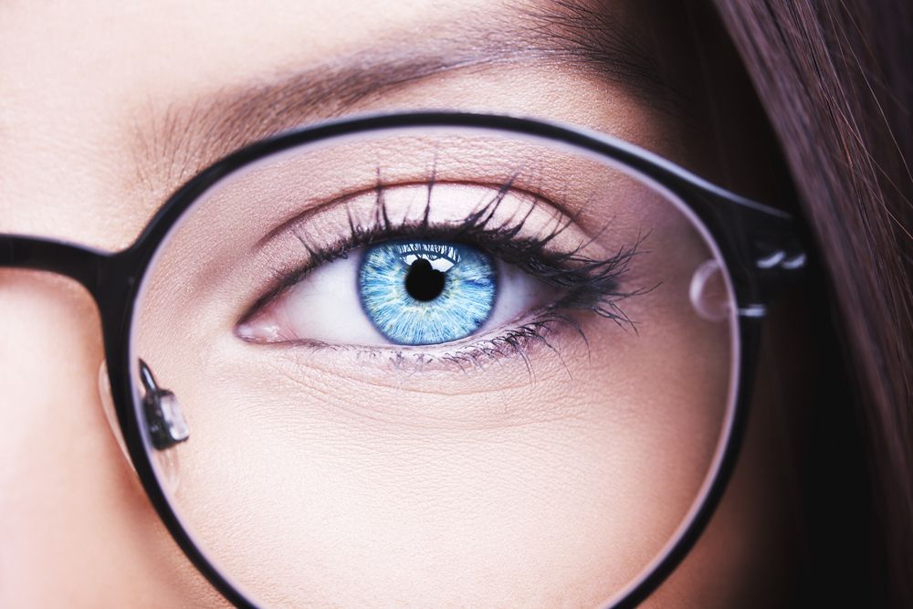 Up close view of a woman's blue eye with large black eyeglasses frames