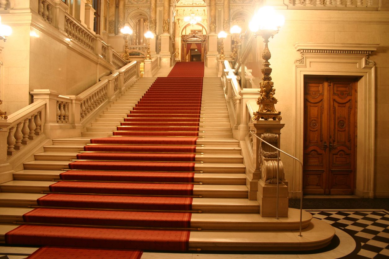 Large patrician staircase with iconic red carpet, with soft lighting and architecture