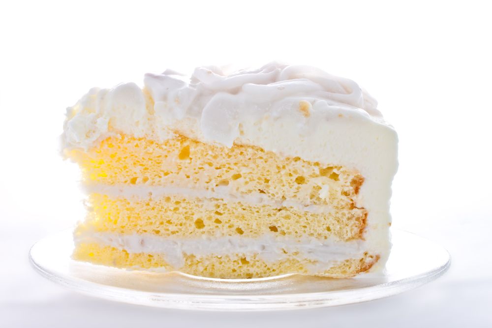 Piece of white vanilla cake on white plate with white background