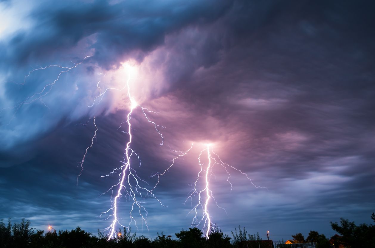 Strikes of lightning comes through purple and blue clouds