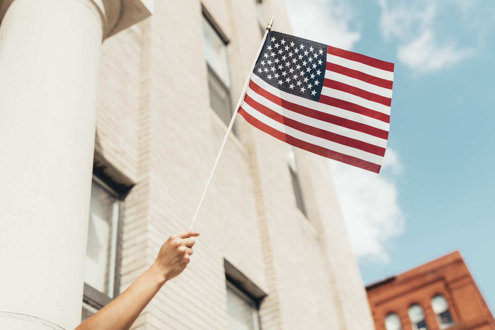Person holding the American flag in front of a building