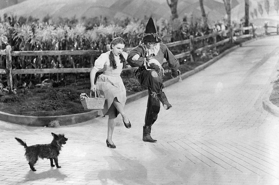 Dorothy with Toto and the Scarecrow on the yellow brick road