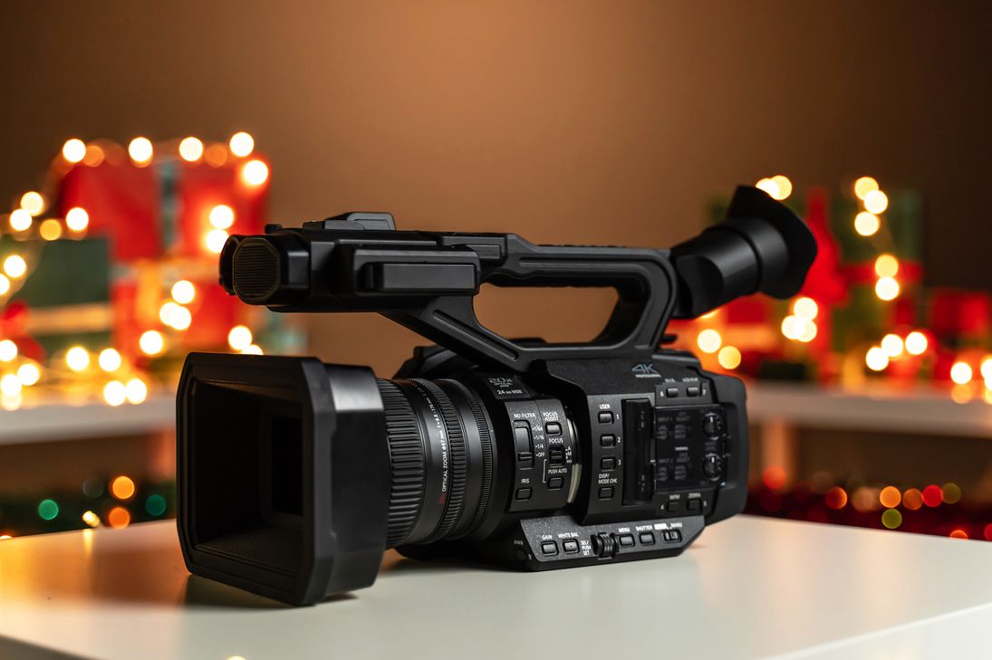 Movie filming camera sitting on a white surface with Christmas lights out of focus in the background