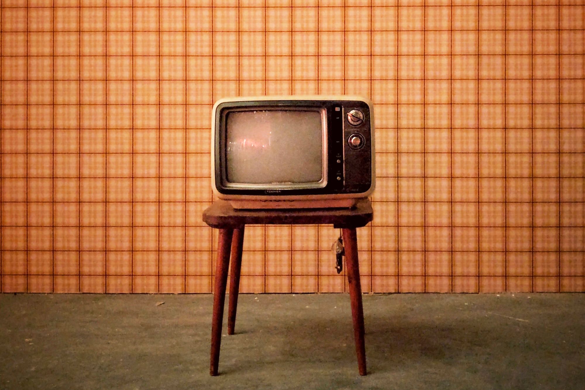 A vintage television set on a wooden stool