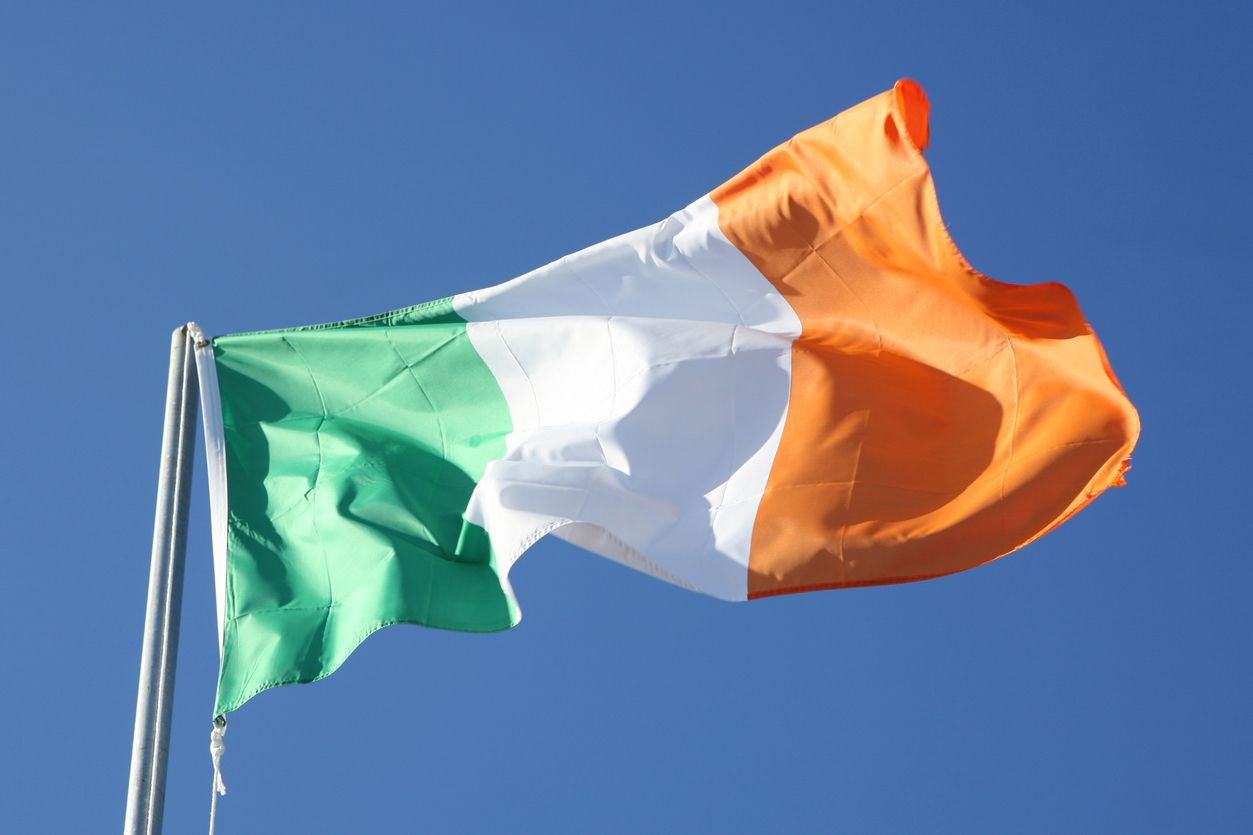 The Irish flag with a blue sky in the background