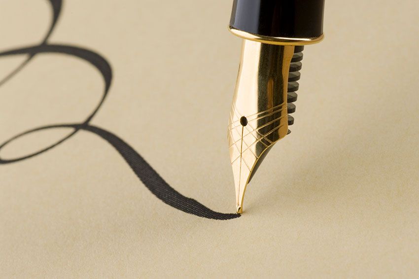 Close up of a calligraphy pen writing on paper.