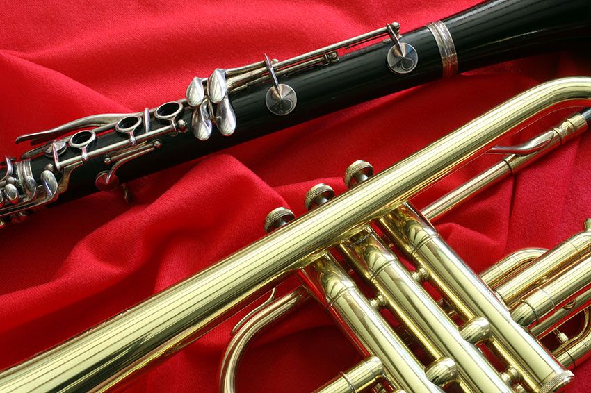Close up of a clarinet and trumpet on a red cloth.