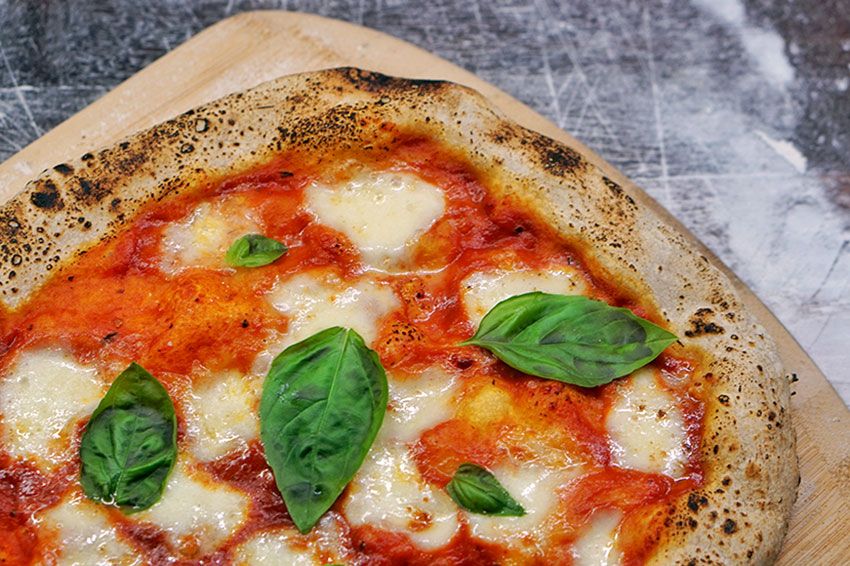 A pizza pie on a wooden board.