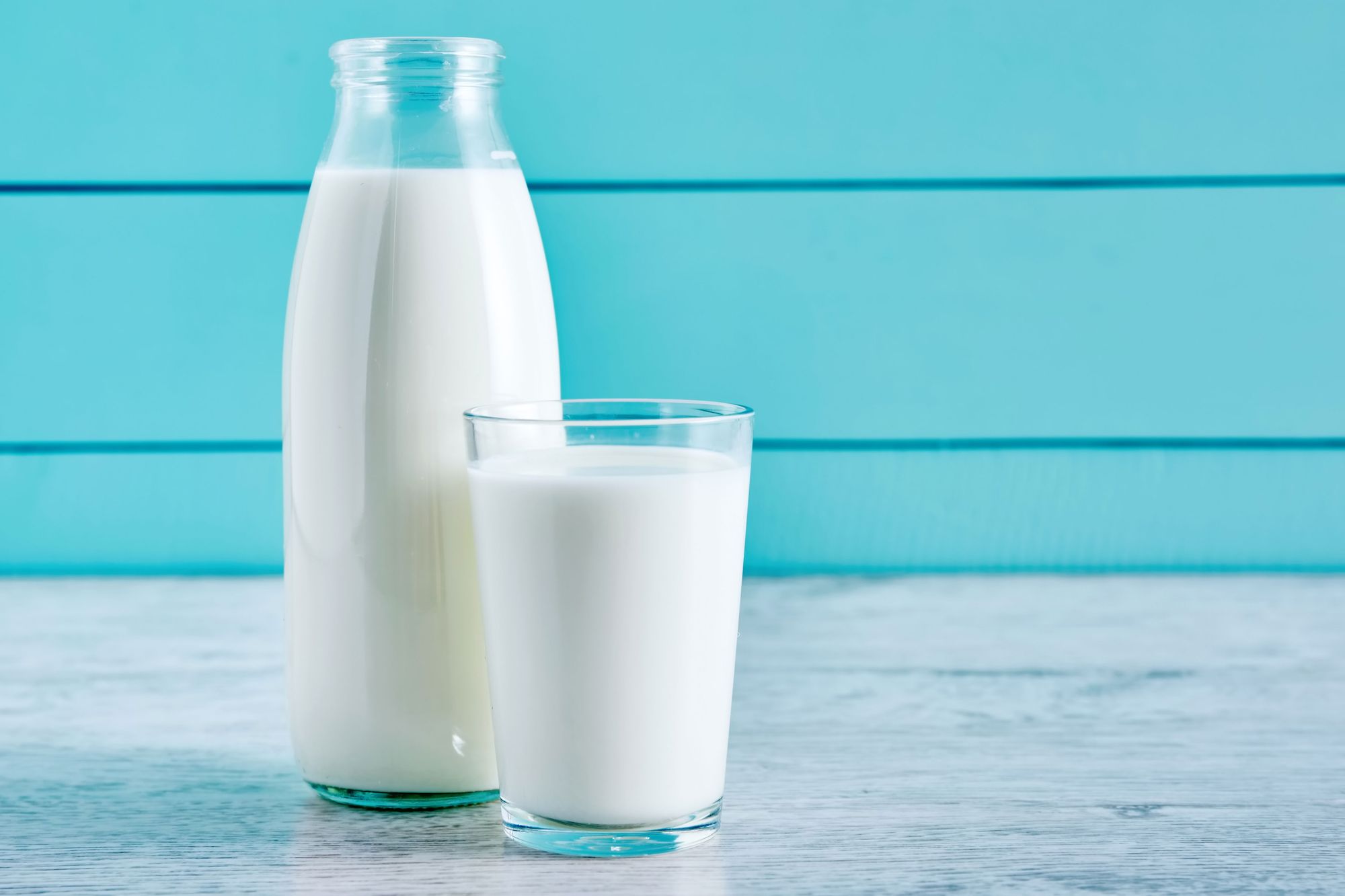 A jug and glass of milk against a blue background.