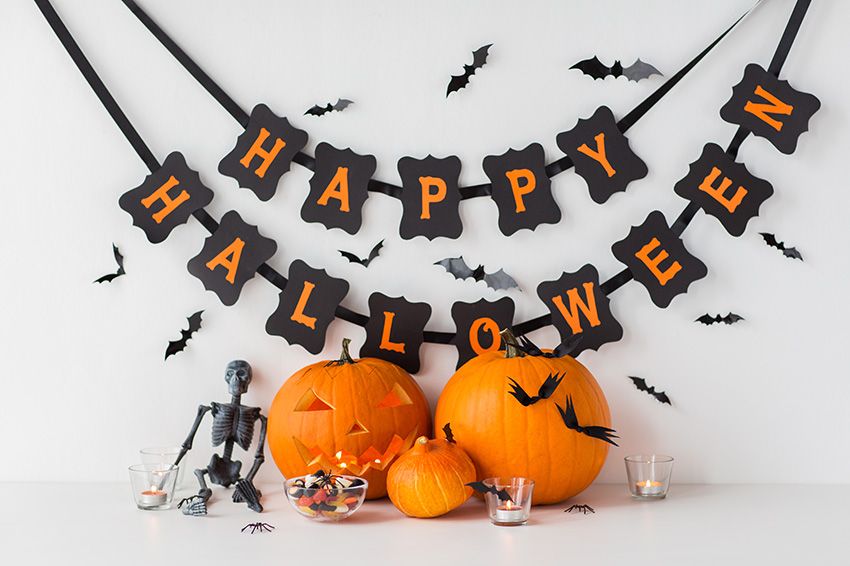 A banner saying "Happy Halloween" with pumpkins, bats, candles and a small skeleton. 