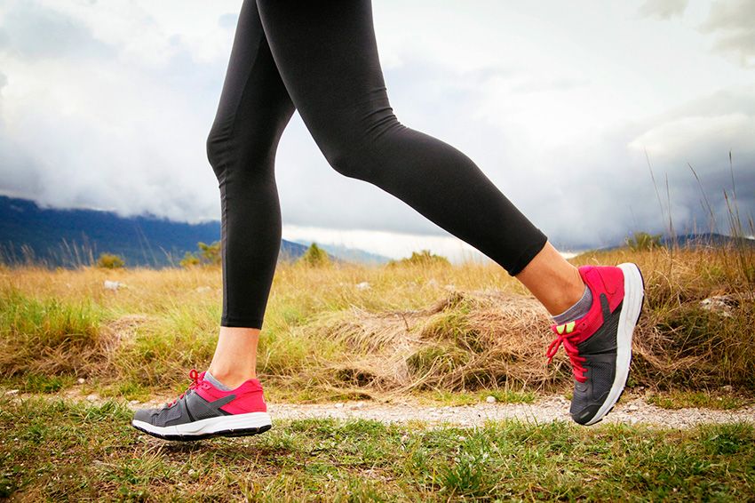Woman's legs running over the wild terrain, under the cloudy sky.