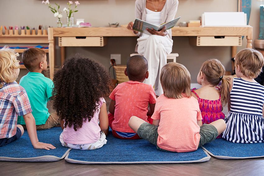 Woman in front reading to a group of children sitting on the floor.