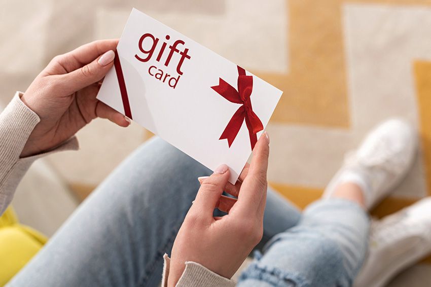 Cropped view of girl holding gift card with red bow.