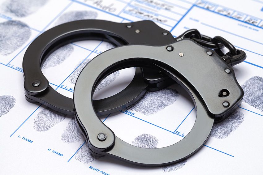 Black handcuffs over chart with fingerprints.