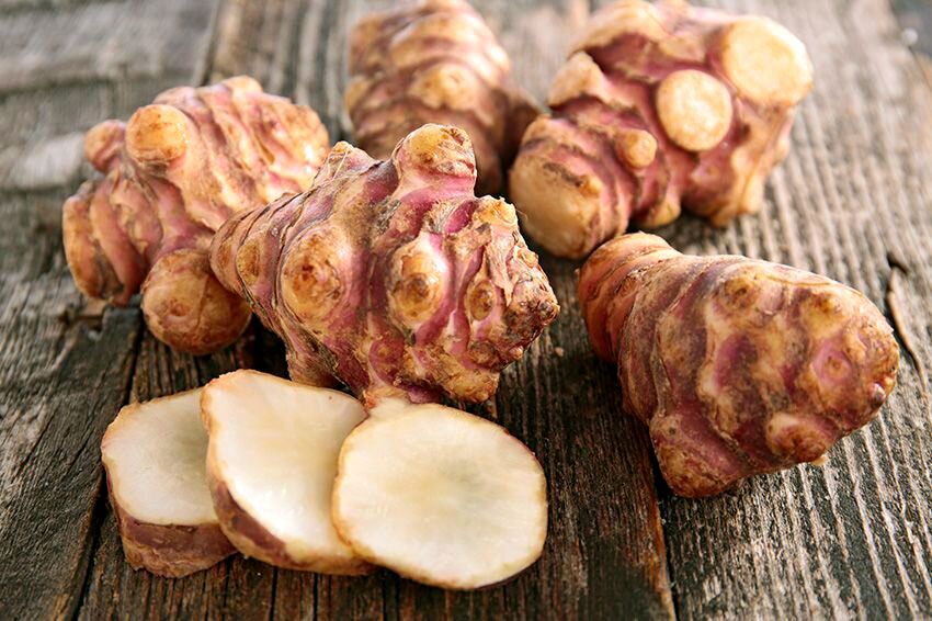 Jerusalem artichokes on wooden table.